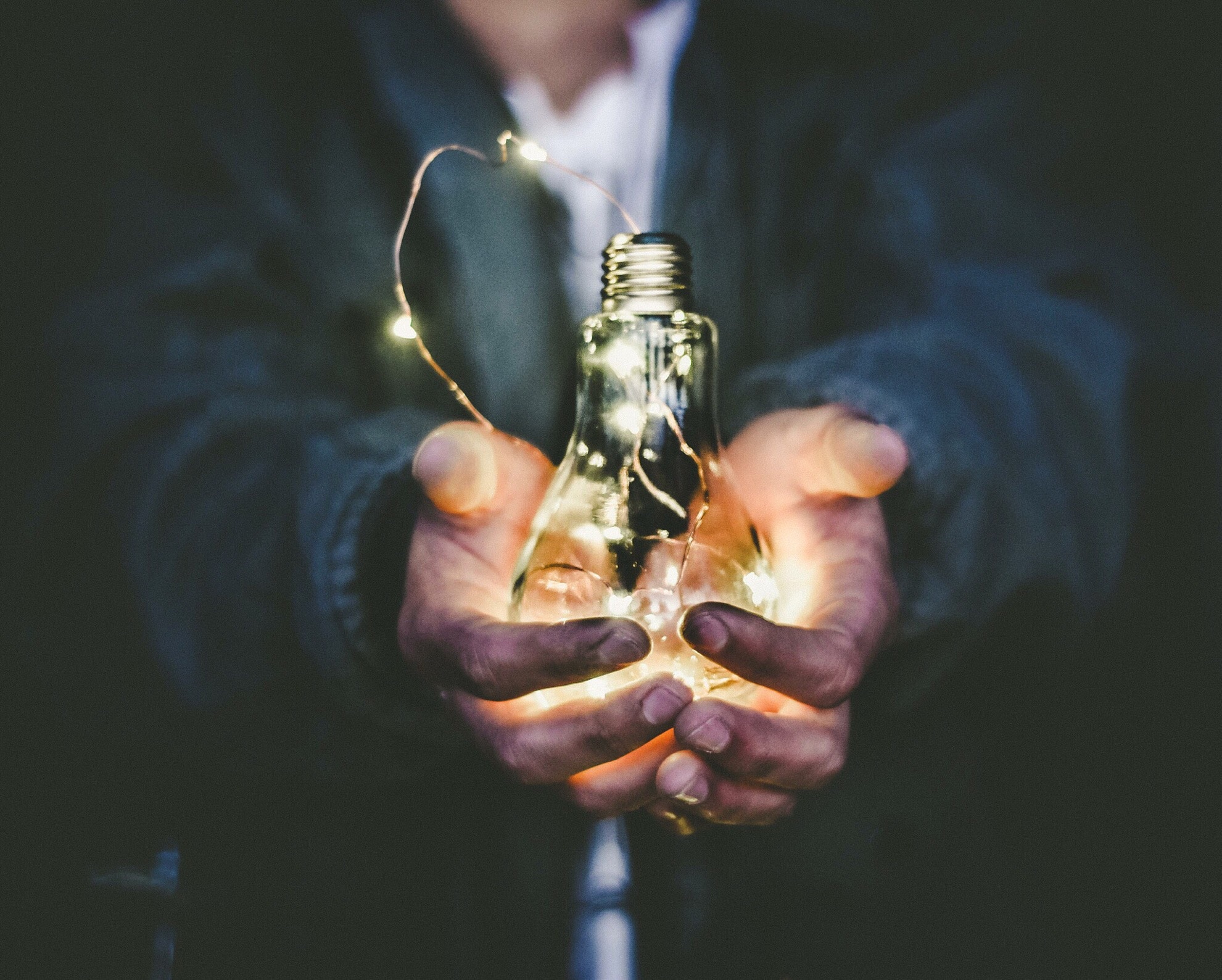 A man holding an illuminated light bulb.